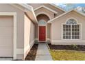 Close up of the front door, an arched window, and simple landscaping at 113 Glasgow Ct, Davenport, FL 33897