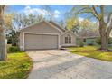 Beige single Gathering home featuring a two-car garage, red door, and simple landscaping at 113 Glasgow Ct, Davenport, FL 33897