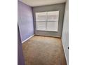 Cozy carpeted bedroom with fresh purple paint and bright natural light from the window at 15688 Galbi Dr, Orlando, FL 32828
