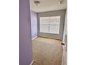 Cozy carpeted bedroom with fresh purple paint and bright natural light from the window at 15688 Galbi Dr, Orlando, FL 32828