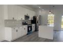 Modern kitchen featuring white cabinets, black hardware, stainless appliances and a center island with quartz countertops at 245 Marion Oaks Golf Rd, Ocala, FL 34473