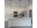 A bright kitchen features white cabinets, modern stainless appliances, kitchen island with a black faucet, and pendant lights at 245 Marion Oaks Golf Rd, Ocala, FL 34473