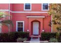 Close up of a pink townhome with a white door, tile awning, and well-maintained landscaping at 3008 Secret Lake Dr, Kissimmee, FL 34747