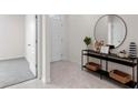 Stylish entryway featuring a console table with decorative items, a round mirror, and neutral tile flooring at 4597 Boxwood Way, Mount Dora, FL 32757