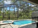 Sparkling screened-in pool and jacuzzi surrounded by a brick-paved patio and lush greenery at 8949 Coconut Breeze Dr, Kissimmee, FL 34747