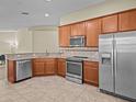 Modern kitchen featuring stainless steel appliances, wooden cabinets and granite countertops at 1208 Bella Rose Ct, Davenport, FL 33896
