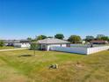 Rear exterior view of a home with green lawn, new construction, and white vinyl fence at 12524 Garrett Pl, Grand Island, FL 32735