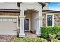 Inviting entrance to a two-story home with decorative columns and stone accents by the garage at 1454 Belle Terre Rd, Davenport, FL 33896