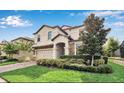 Well-maintained two-story home with lush landscaping, stone accents, and a brick driveway at 1454 Belle Terre Rd, Davenport, FL 33896