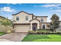 Beautiful two-story home with a well-maintained lawn, brick driveway and lush landscaping at 1454 Belle Terre Rd, Davenport, FL 33896