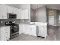 Well-equipped kitchen featuring stainless steel appliances, gray backsplash, and white cabinets at 15832 Autumn Glen Ave, Clermont, FL 34714
