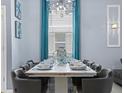 Formal dining room with elegant table setting, modern chandelier, and blue drapes at 2221 Lelani Cir, Davenport, FL 33897