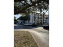 View of the condo building from the parking lot, with mature shade trees, sidewalks, and green spaces at 4024 Breakview Dr # 10804, Orlando, FL 32819