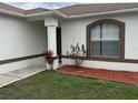 Close up shot of a home's exterior showcasing a columned entryway, flower beds, and a large window at 649 Gazelle Dr, Kissimmee, FL 34759
