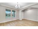 Bright and airy living room with decorative tray ceiling, two windows, and light wood-look tile flooring at 16207 Point Rock Dr, Winter Garden, FL 34787