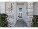 Elegant townhouse entryway featuring stone accents, a glass front door, and manicured bushes at 17442 Hidden Forest Dr, Clermont, FL 34714