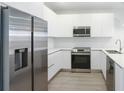Modern kitchen features stainless steel appliances, sleek white cabinets, and hardwood floors at 17442 Hidden Forest Dr, Clermont, FL 34714