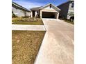 Tan single-story home with an open two-car garage, driveway and manicured landscaping at 1972 Victoria St, Davenport, FL 33837