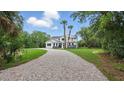 Distant full front of a new construction house with mature trees and a long gravel driveway at 2650 Howard Ave, Oviedo, FL 32765