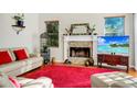 Bright living room with a stone fireplace, red rug, and comfortable white couches provides a cozy place for relaxation at 3518 Edlingham Ct, Belle Isle, FL 32812
