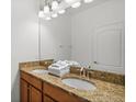 Bathroom featuring double sinks with granite countertops and wood cabinetry at 8990 Cuban Palm Rd, Kissimmee, FL 34747
