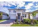 Beautiful two-story home with a brick driveway, landscaped yard, and a covered entryway at 187 Aces High Ln, Davenport, FL 33896