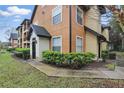 Exterior view of condo with manicured shrubs, a covered entryway, and a well-maintained lawn area at 6071 Westgate Dr # 312, Orlando, FL 32835