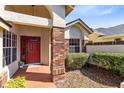 Inviting front porch with a red door, brick columns, and manicured landscaping and brick walkway at 702 Barrington Cir, Winter Springs, FL 32708