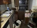 Cluttered, damaged kitchen in disrepair with dated appliances at 8320 Dominguin St, Orlando, FL 32817