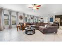 Spacious living room with tile floors, a ceiling fan, large windows, and a comfortable, oversized sectional sofa at 9518 Lynwood St, Clermont, FL 34711