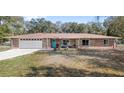 Inviting brick home with a two-car garage, blue front door, and cozy front porch seating at 11595 Sw 134 Ct, Dunnellon, FL 34432