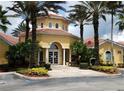 Exterior of clubhouse featuring a red tile roof, arched entrance, and lush tropical landscaping at 12204 Wild Iris Way # 109, Orlando, FL 32837