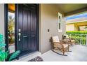 Inviting front porch features rocking chairs, a dark front door, and lush landscaping at 14664 Spotted Sandpiper Blvd, Winter Garden, FL 34787