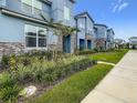 Beautiful street view of modern townhomes with stone accents, landscaped yards, and well-maintained sidewalks at 2182 Cooper Bell Pl, Kissimmee, FL 34747