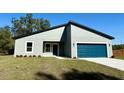 Inviting single-story home featuring modern architecture, tidy landscaping, and a striking blue garage door at 2249 Sw 146 Loop, Ocala, FL 34473