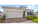 A single-story home featuring a two-car garage, a brick-paved driveway and lush green lawn at 5593 Vigo Loop, St Cloud, FL 34771