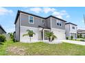 View of a two-story home with gray siding, a white garage door, manicured lawn, and decorative rock and shrub accents at 5663 Keaton Springs Dr, Lakeland, FL 33811