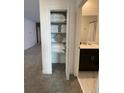 Hallway featuring an open closet, leading to a bathroom with a dark vanity and light countertops at 695 Whistling Straits Blvd, Davenport, FL 33896