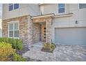 Charming home exterior highlighting a stone entryway, well-kept landscaping, and a paver walkway to the front door at 8903 Caroline Bay Ct, Kissimmee, FL 34747