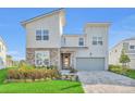 Contemporary two-story home with a stone facade, well-manicured landscaping, and a paved driveway leading to a garage at 8903 Caroline Bay Ct, Kissimmee, FL 34747