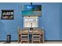 Cozy dining area with a wooden table set, a flat-screen TV, and charming decor against a vibrant blue wall at 1417 Independence Ave, Deltona, FL 32725