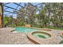 Inviting screened-in pool with a spa and a calming waterfall feature surrounded by brick pavers at 210 Torcaso Ct, Winter Springs, FL 32708