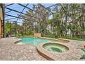 Relaxing screened-in pool with a spa, waterfall feature, and lush tropical landscaping at 210 Torcaso Ct, Winter Springs, FL 32708