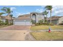 Charming two-story home with a manicured lawn, palm trees, and a brick driveway at 23431 Companero Dr, Sorrento, FL 32776