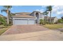 Charming two-story home with a manicured lawn, palm trees, and a brick driveway at 23431 Companero Dr, Sorrento, FL 32776