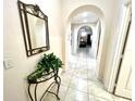 Inviting hallway with tiled floors, arched doorways, and decorative mirror and table at 3050 Pirates Retreat Ct # 103, Kissimmee, FL 34747