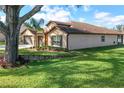 Exterior side view of home with well maintained lawn, mature tree, and manicured landscaping at 32107 Spring Meadow Ct., Sorrento, FL 32776