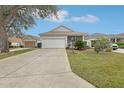 Well-maintained single-story home with a two-car garage and a lush green lawn at 25239 Cranes Roost Cir, Leesburg, FL 34748