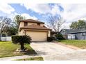 Tan two story home with a light garage door, landscaping, and a walkway leading to the front door at 7440 Windsome Ct, Orlando, FL 32810