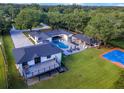 Aerial shot of a modern home with a pool, outdoor seating, lush landscaping, and a sport court at 900 W Plant St, Winter Garden, FL 34787